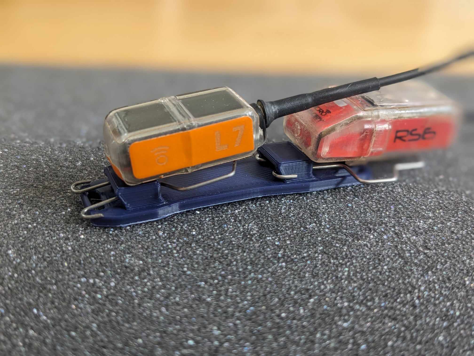 Two GPS trackers clipped to a 3D printed mount for tracking raptors during rehabilitation.