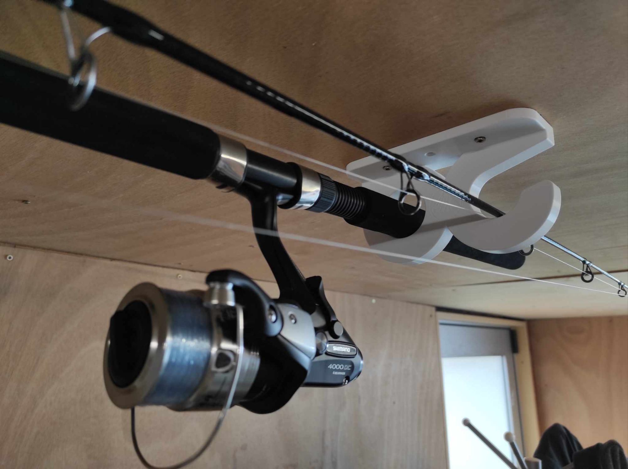 3D printed fishing rod holder on ceiling holding 2 rods.